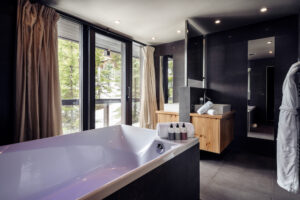 Bathtub in middle of room with windows overlooking ski slopes behind
