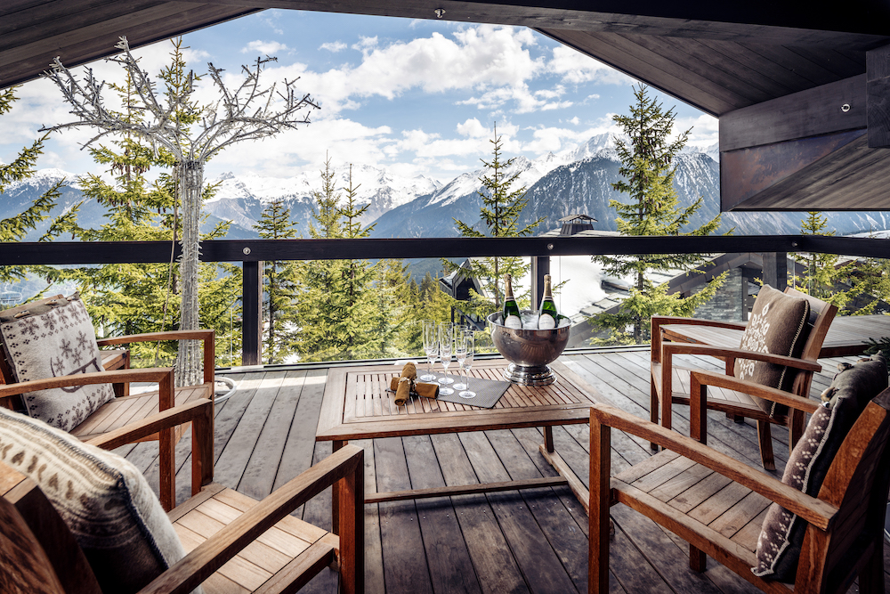 Balcony at Chalet Tahion overlooking mountains, with seating area and champagne on the table